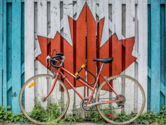 Red road bike beside red and white wooden maple leaf painted wall - Photo by Ali Tawfiq on Unsplash