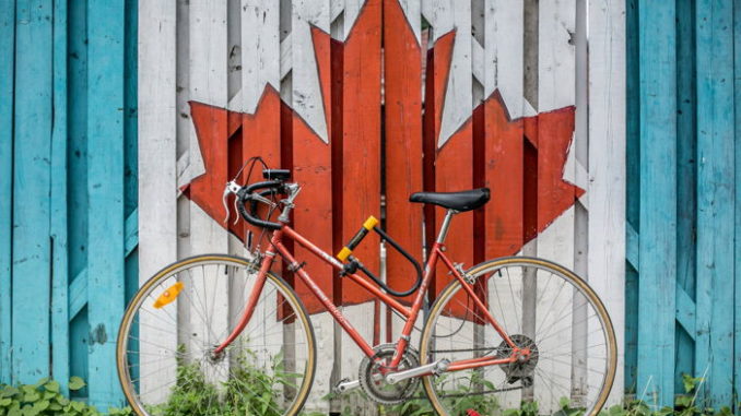 Red road bike beside red and white wooden maple leaf painted wall - Photo by Ali Tawfiq on Unsplash