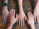 5 hands on a table - Unsplash