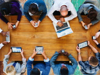 A group of people at a conference table using various mobile devices